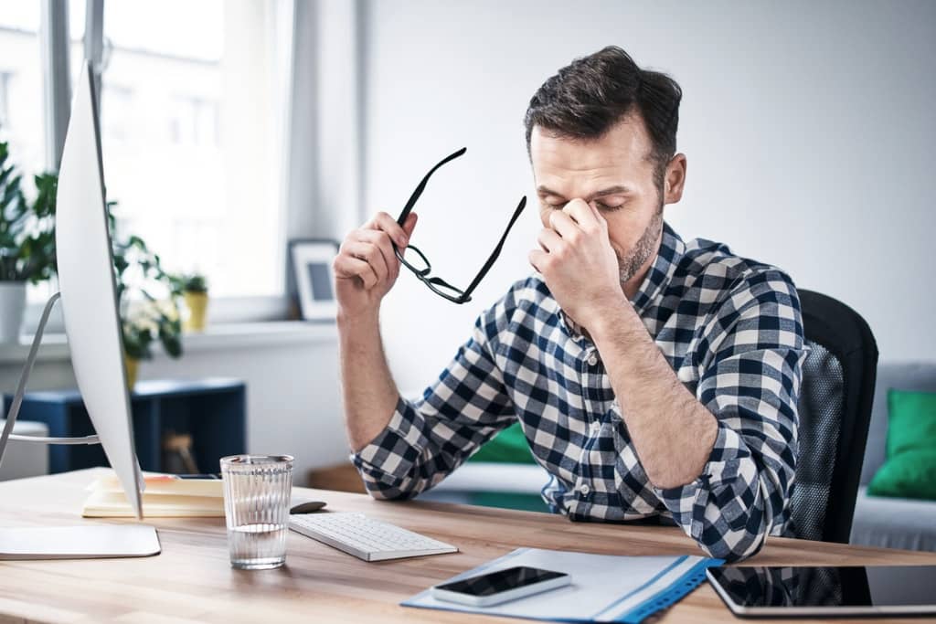 Ein Mann, der am Schreibtisch sitzt und erschöpft ist