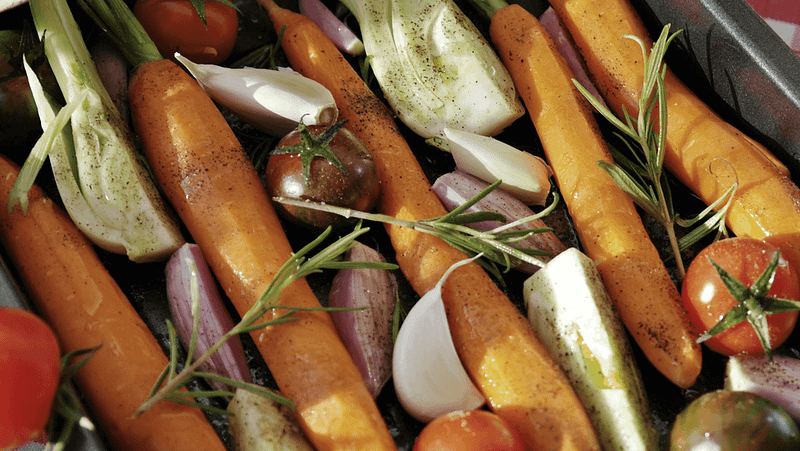 Eine gesunde Gemüsepfanne mit Karotten, Tomaten, Knoblauch, Schalotten und Rosmarin