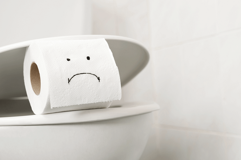 Eine unglückliche Rolle Toilettenpapier schaut aus der Toilette